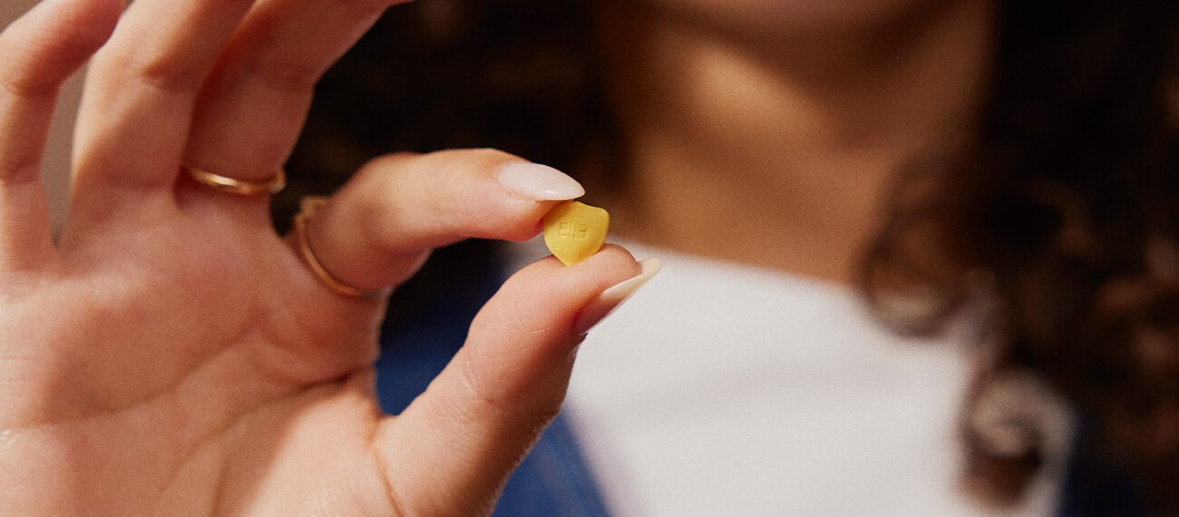 woman holding an ellaone pill in form of a shield